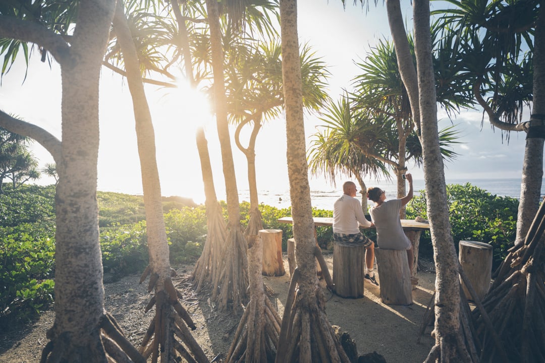 A steaming cup of coffee on a wooden table overlooking the crystal-clear Pacific Ocean at Papaya Villa.